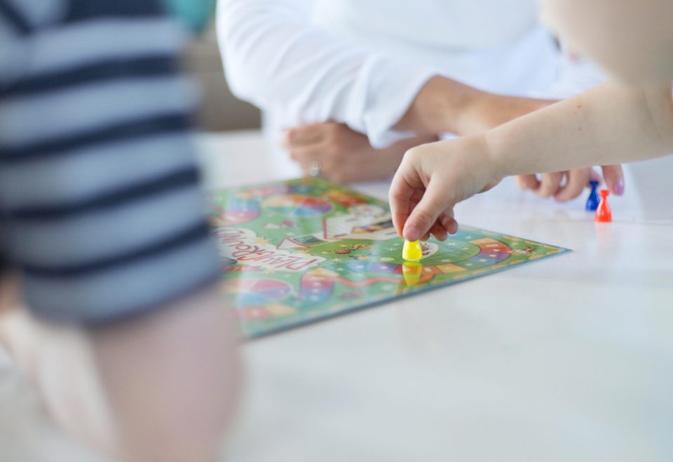 Children's hands moving pieces on a board game at a low table.